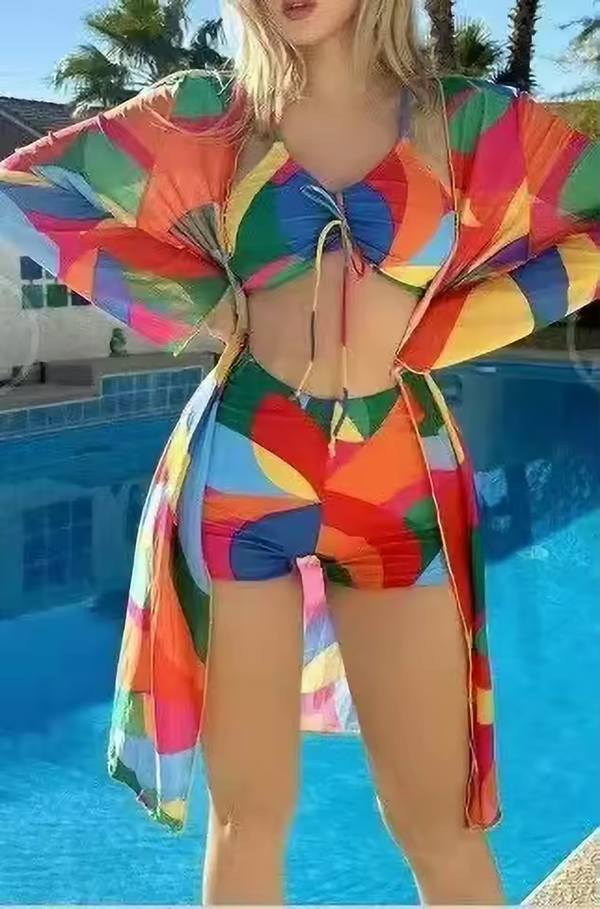 Colorful block print bikini with matching cover-up by the pool, featuring vibrant rainbow geometric pattern and tie-front