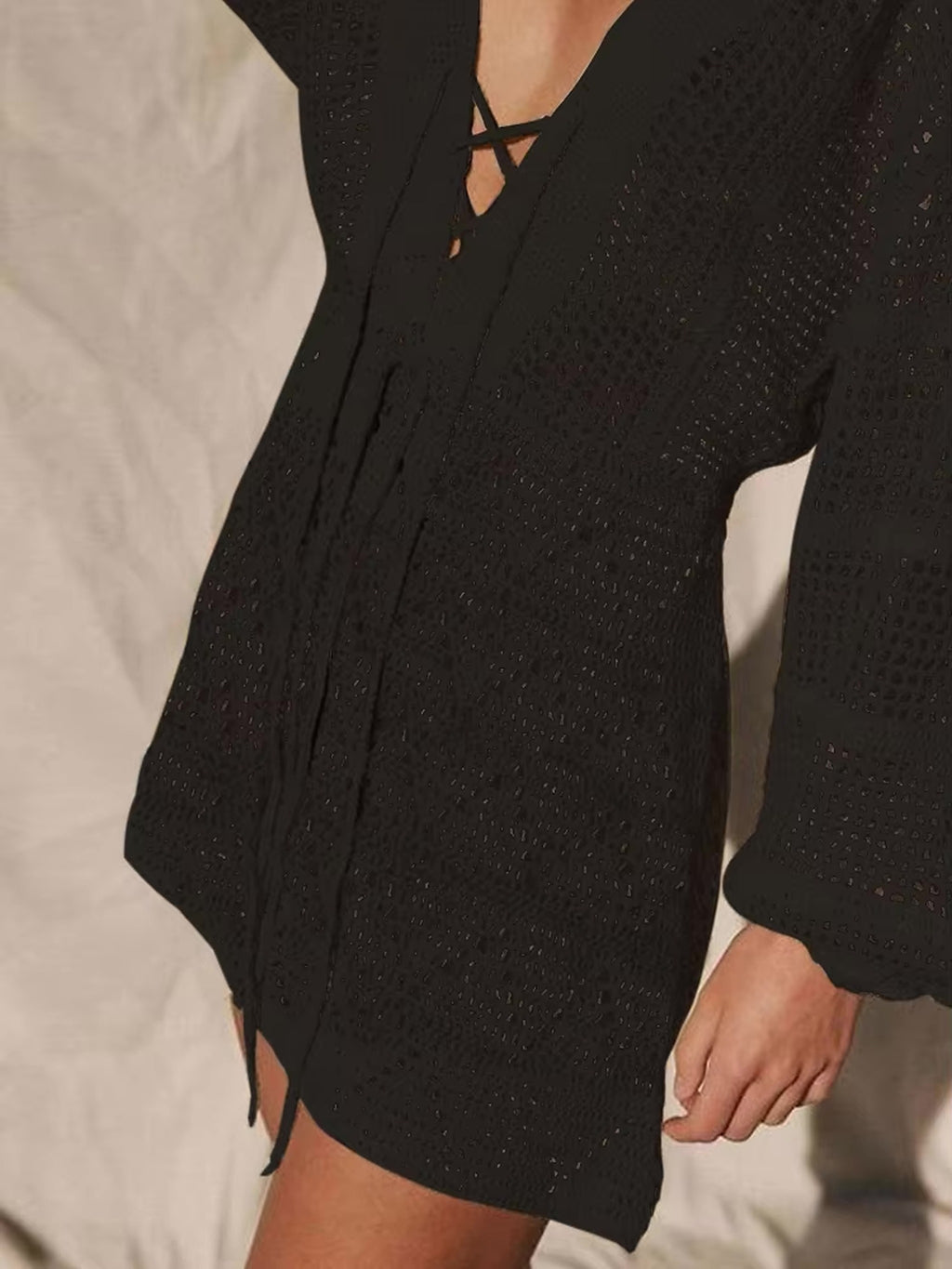 Black long-sleeve knit bikini cover-up with textured fabric and front tie closure detail.