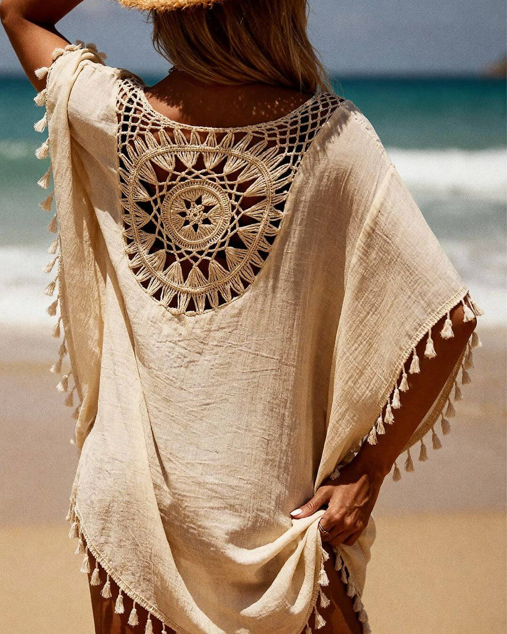 Cream linen beach cover-up dress with intricate crochet back detail and tassel trim at the beach