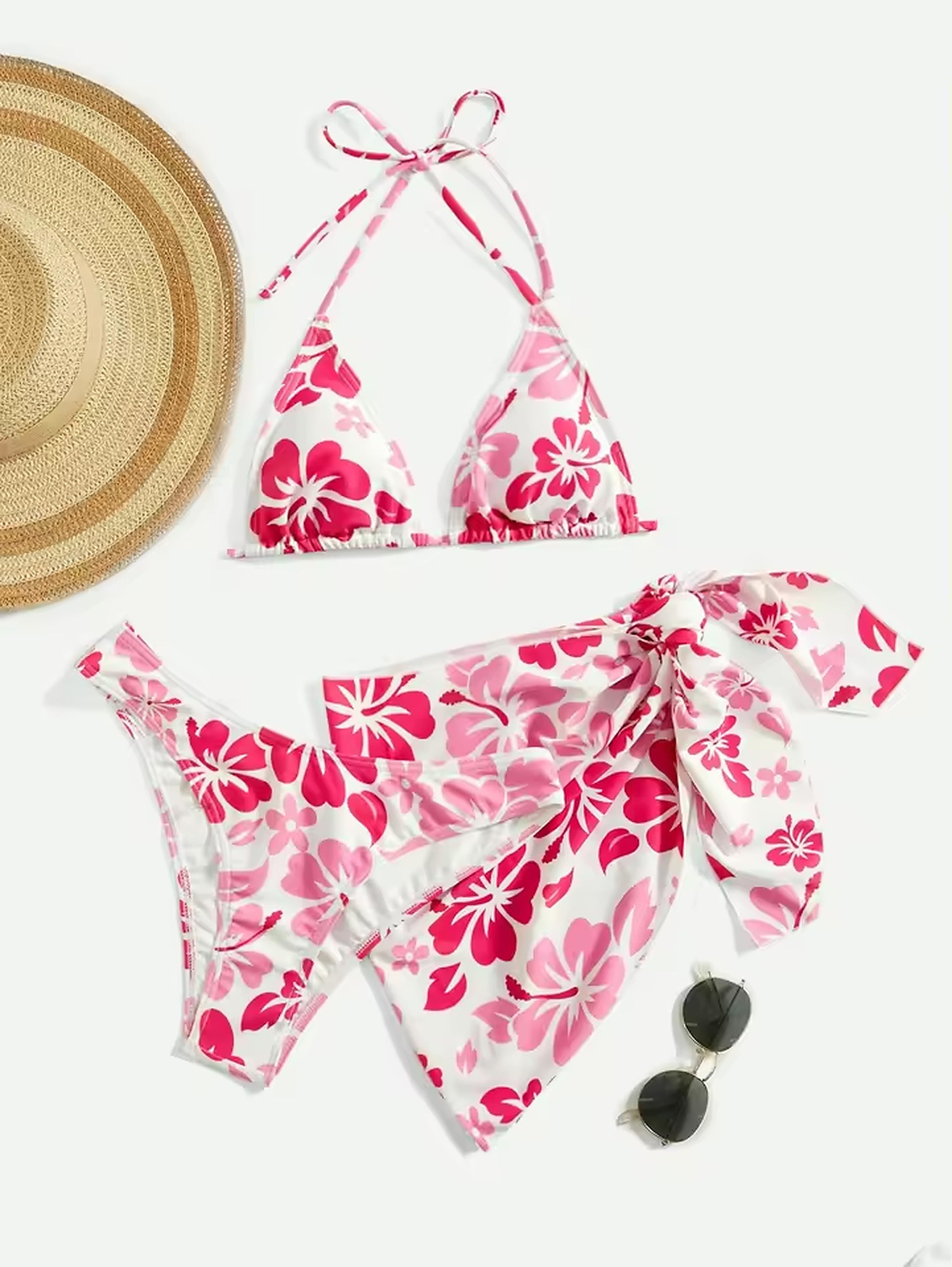 Pink floral bikini with halter top and matching sarong wrap, styled with straw hat and sunglasses.