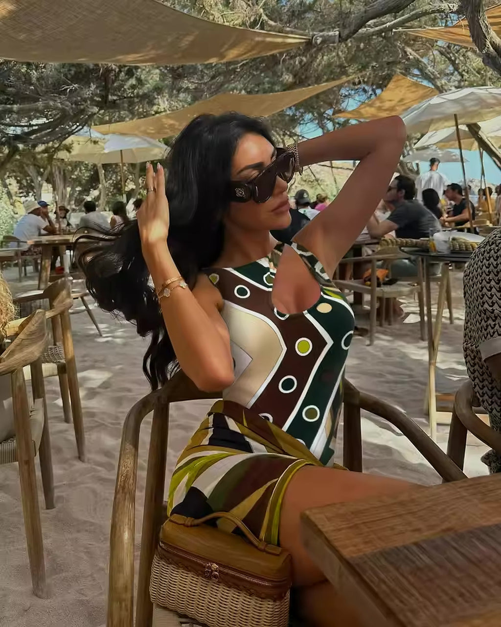 Woman wearing brown and cream geometric patterned bikini at beach café under sail shade