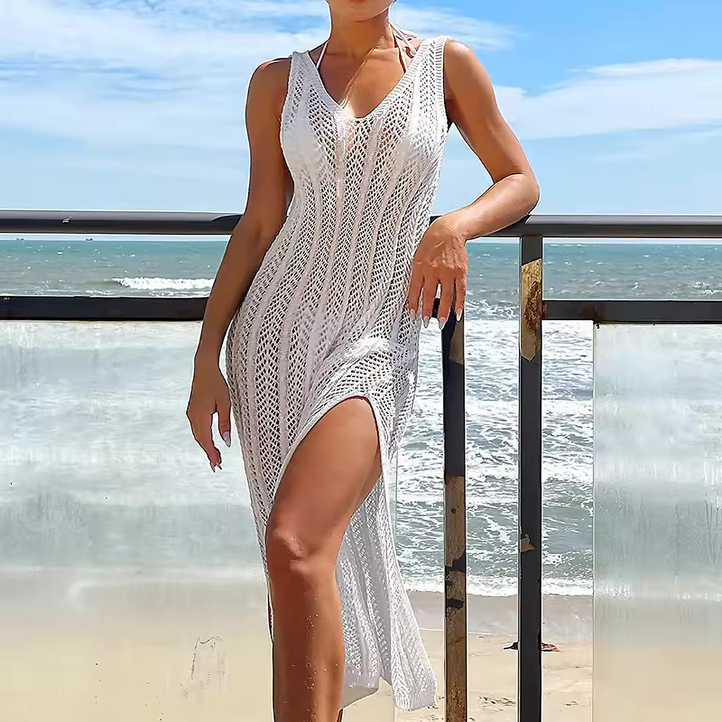 Woman wearing white knit bikini cover-up dress on beach with ocean waves in background