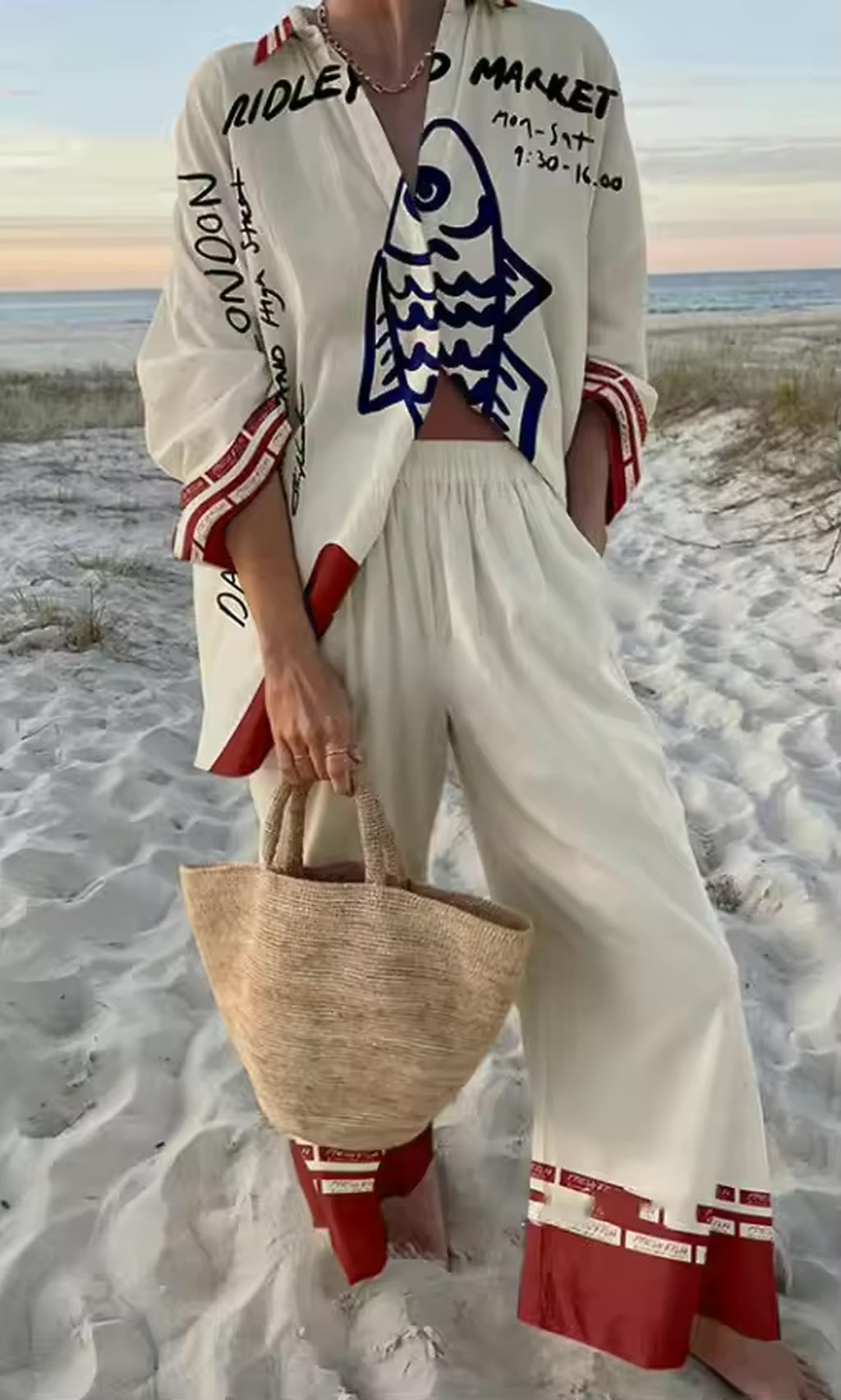 Woman wearing white Savanna Siren bikini with red and navy graphic print on beach at sunset