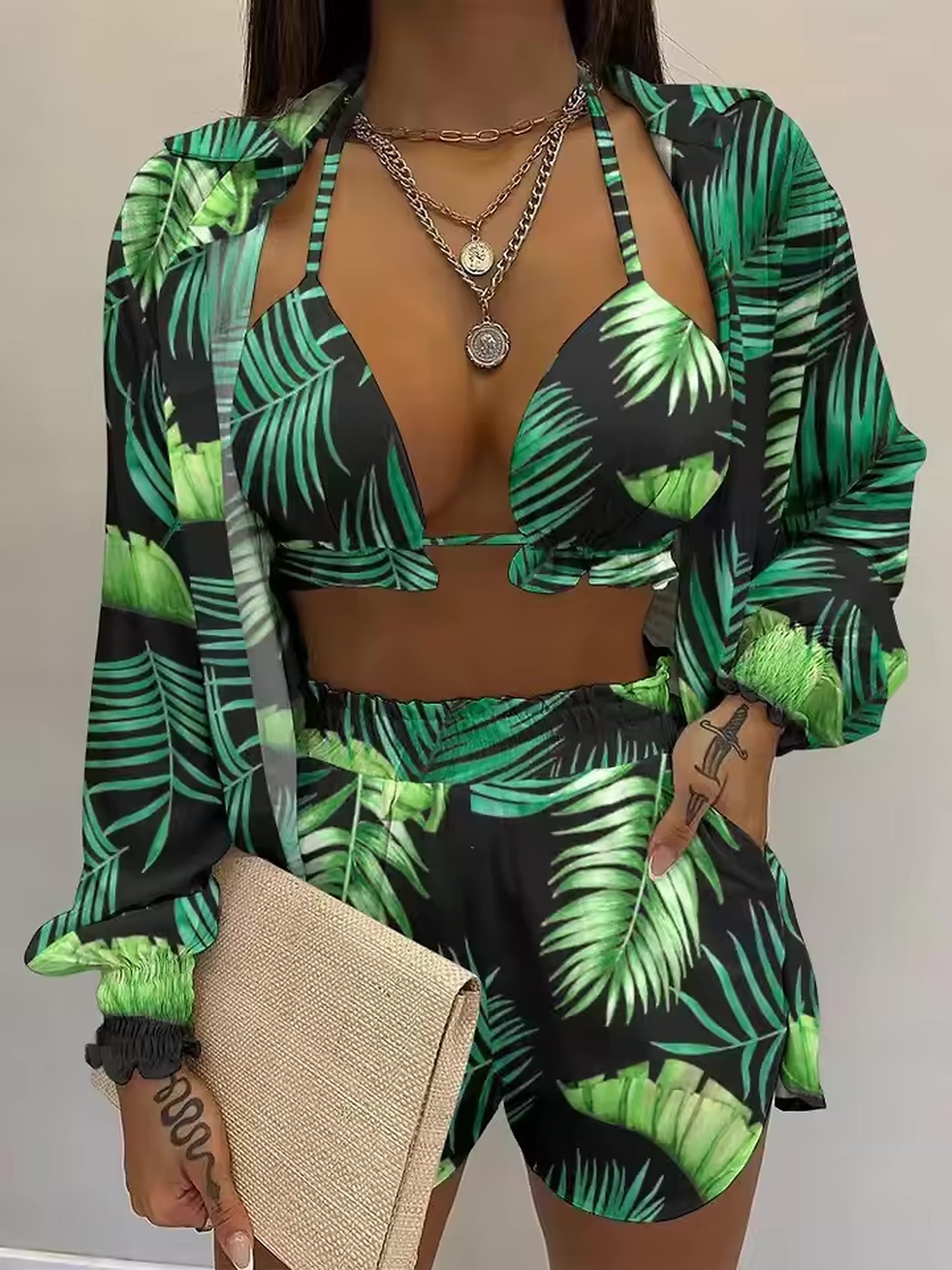 Woman wearing green and black palm leaf print bikini with matching shirt and shorts beach outfit