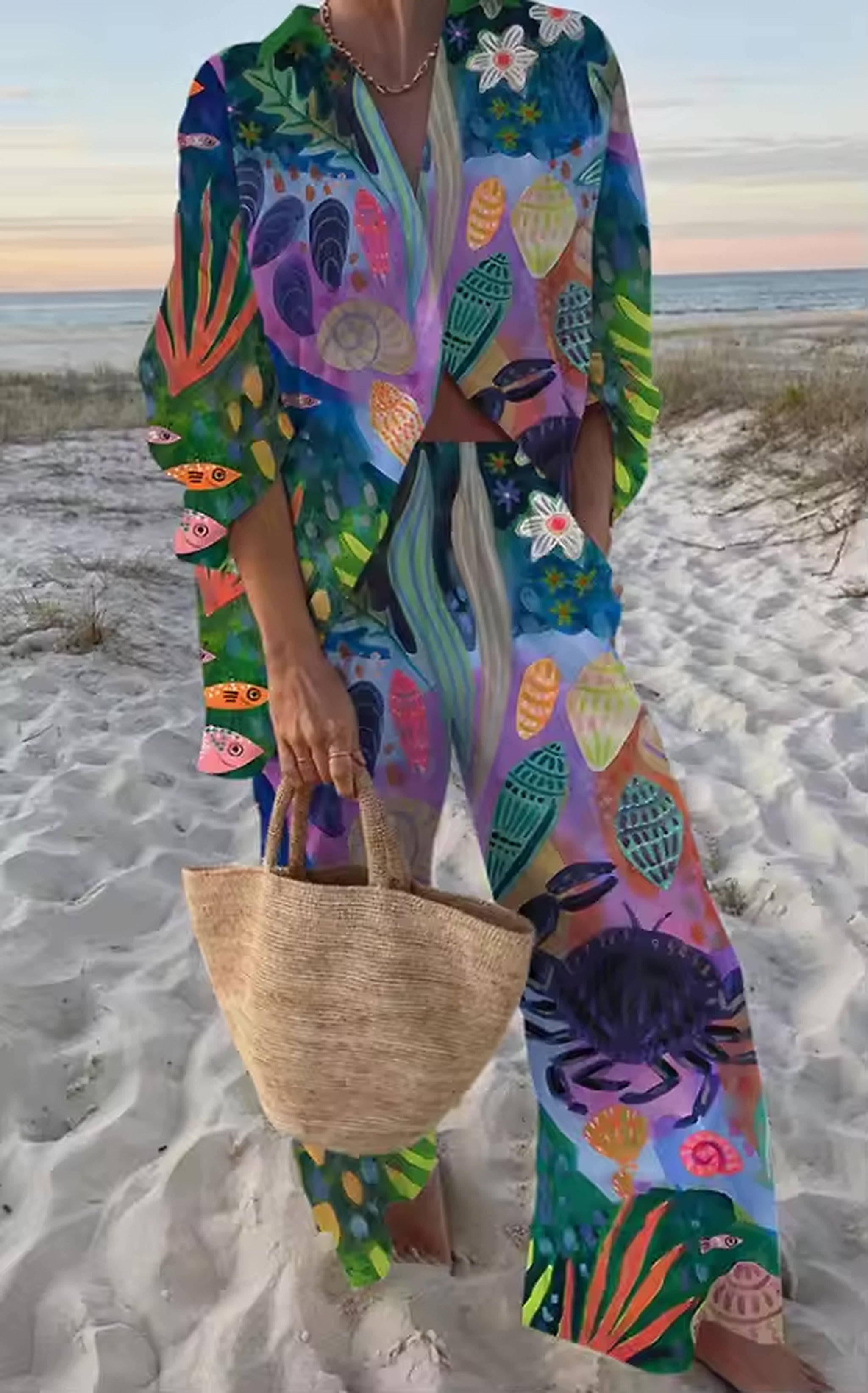Colorful beach cover-up kaftan with vibrant marine life print in blues, purples, and greens worn on sandy beach.