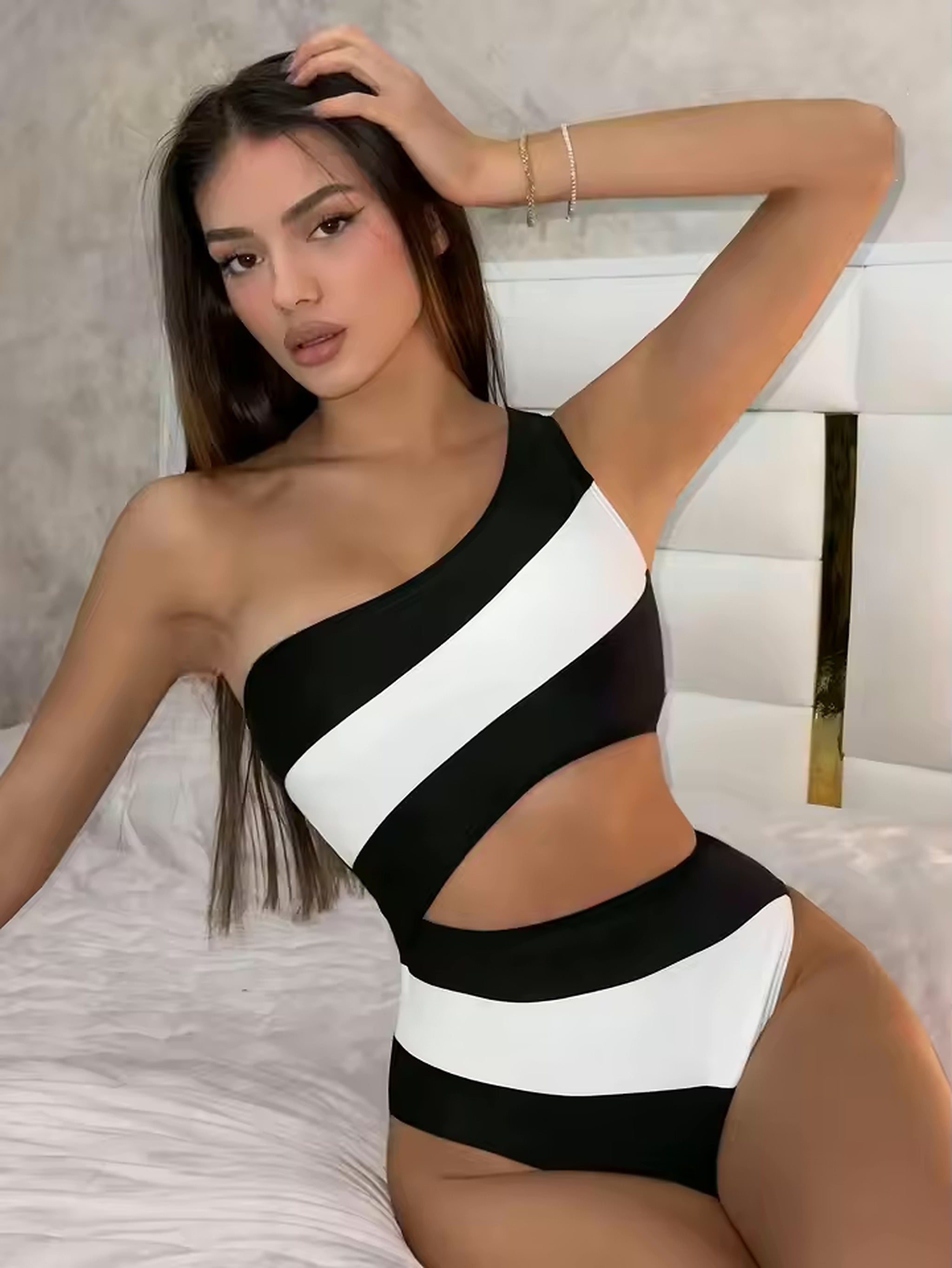 Black and white striped one-piece swimsuit with asymmetrical neckline and cutout details on model