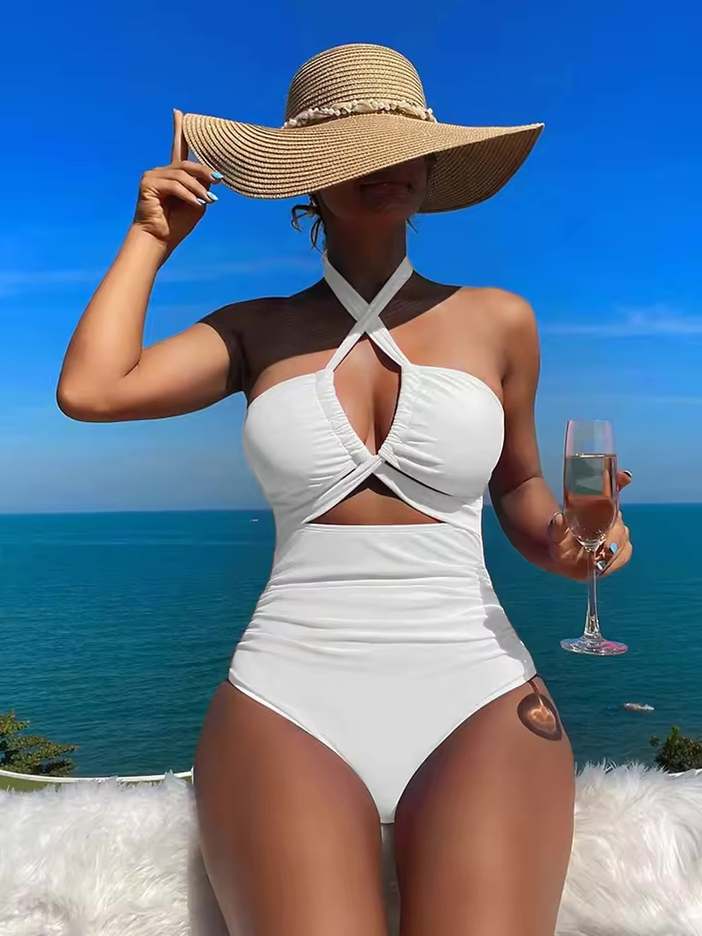 White halter bikini with cutout detail worn by woman in straw hat by ocean
