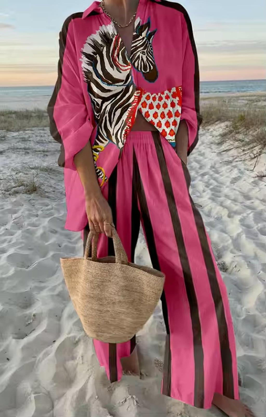 Pink and black zebra print bikini top with red patterned shorts, styled on sandy beach at sunset