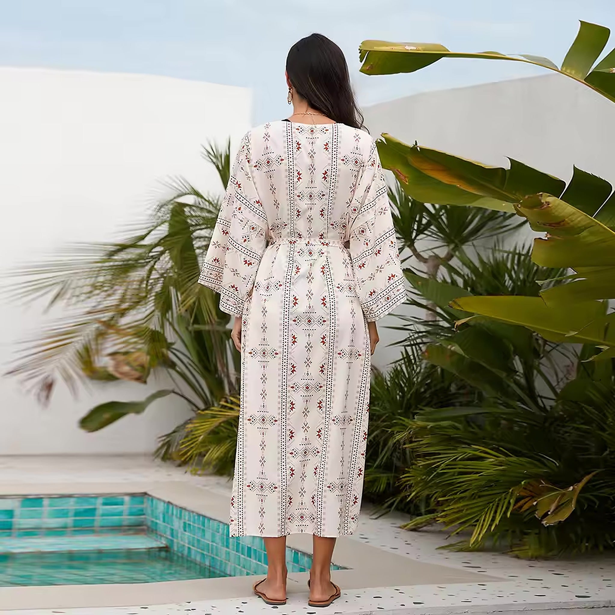 Woman wearing cream crochet cover-up with geometric pattern by the pool and tropical plants