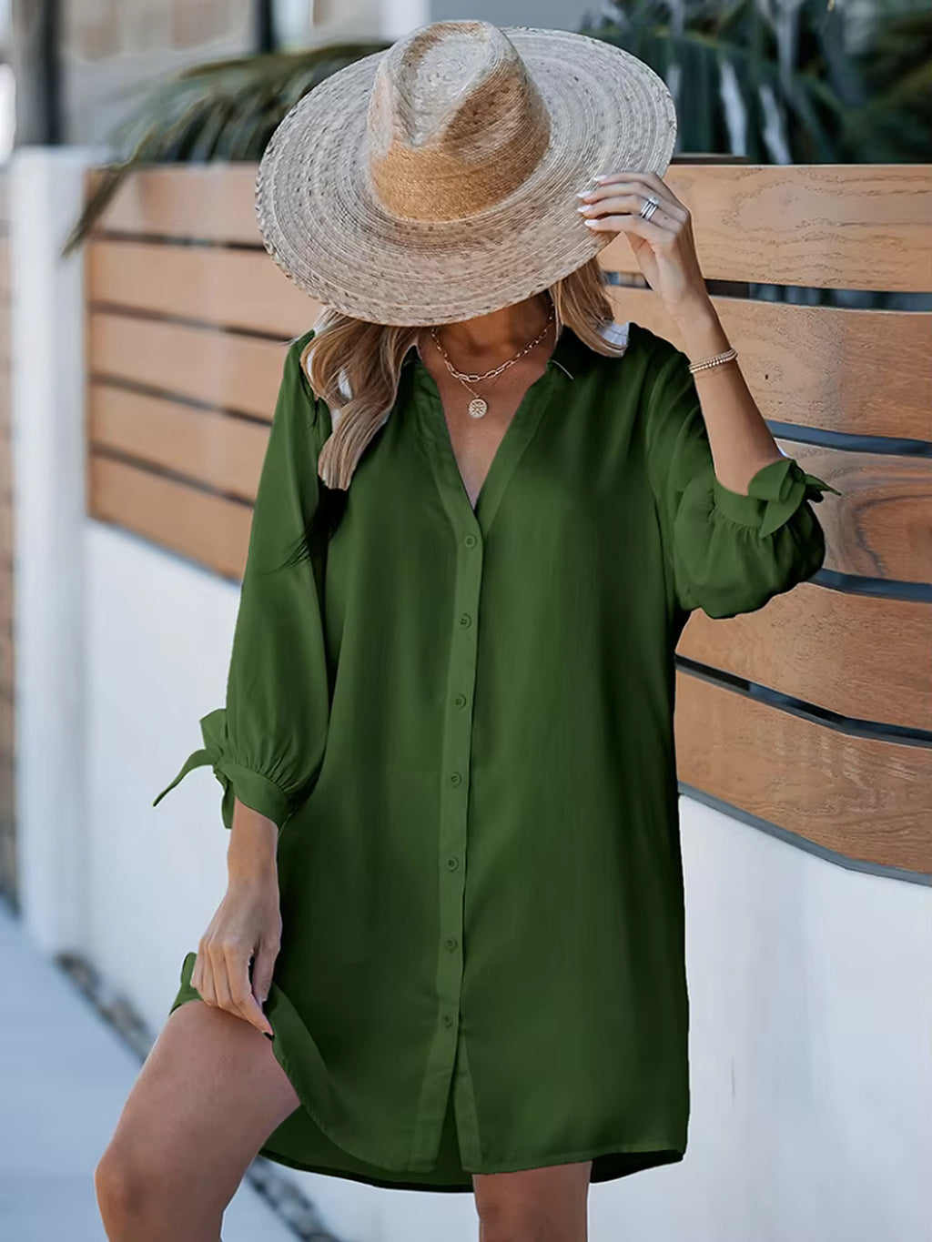Woman wearing green button-up beach shirt over bikini, paired with straw hat and gold jewelry