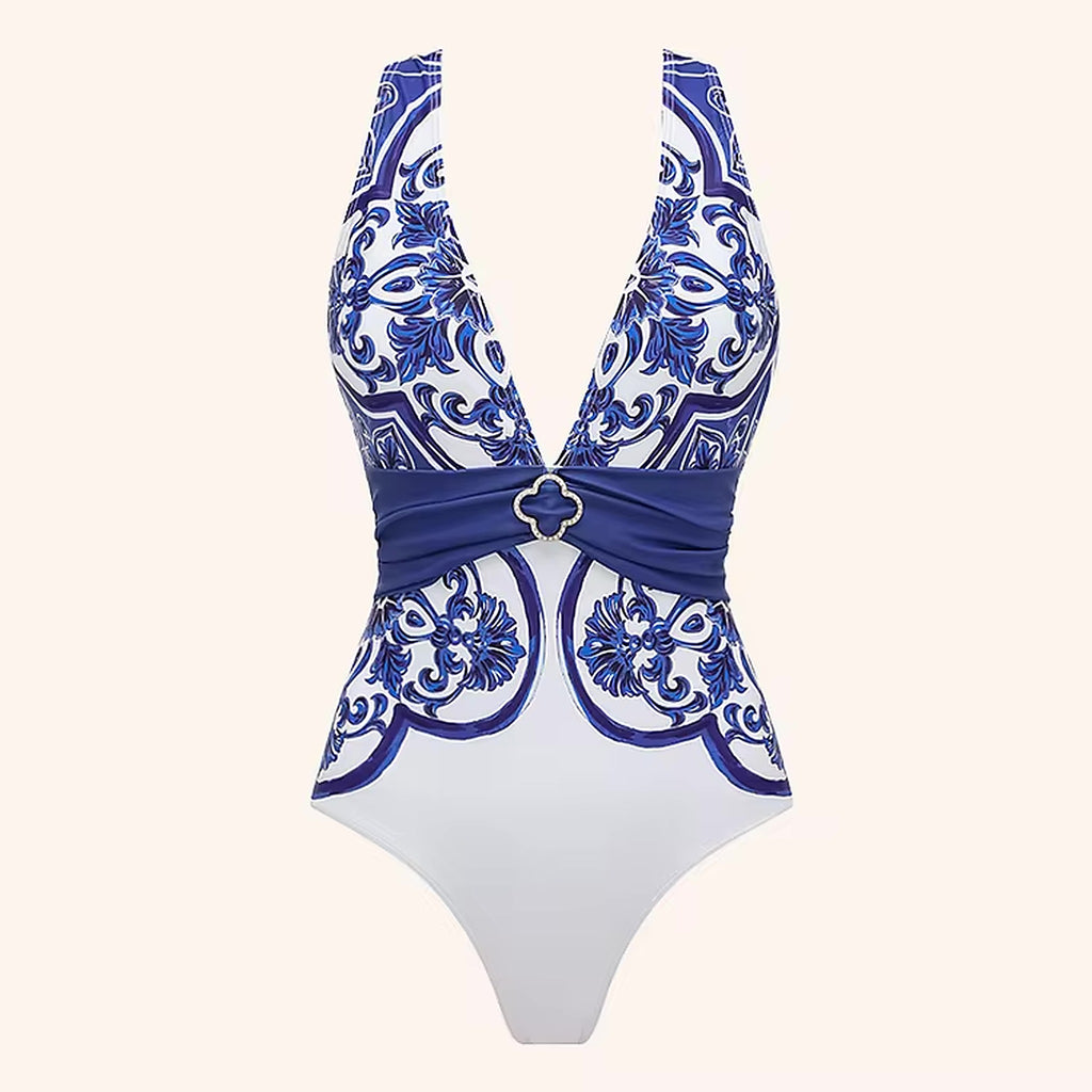 Blue and white patterned one-piece swimsuit with ornate baroque print, plunging neckline, and coordinating waist band detail.